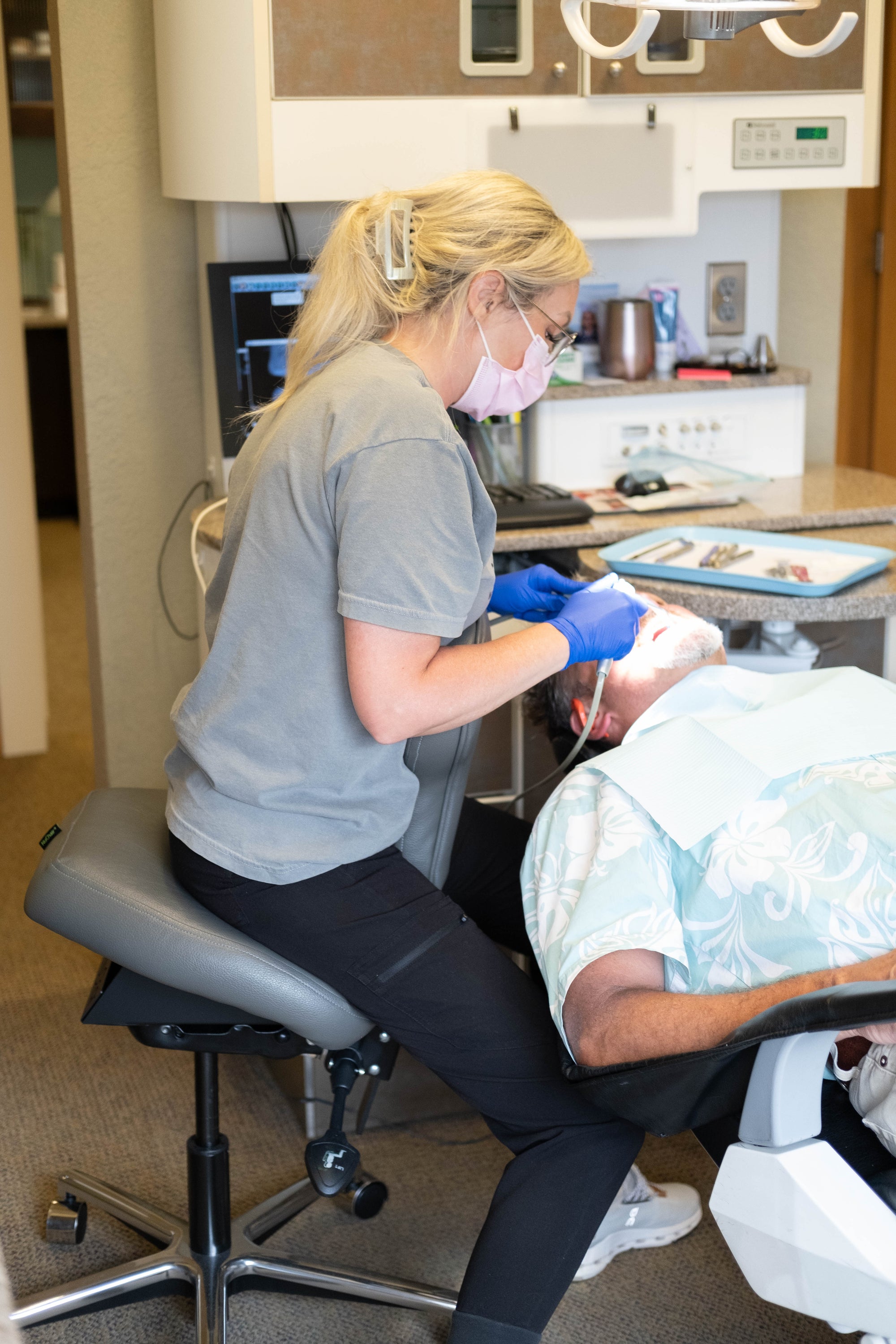 Dentist sitting in a NuChair working on patient