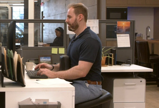 Man sitting in a NuChair working at his computer workstation desk